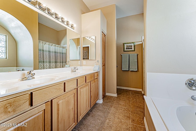 full bathroom with double vanity, tile patterned flooring, a sink, and baseboards