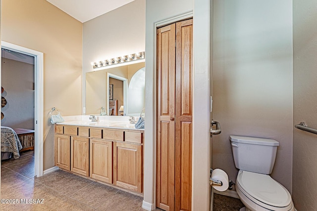 ensuite bathroom featuring connected bathroom, toilet, tile patterned flooring, vanity, and a closet