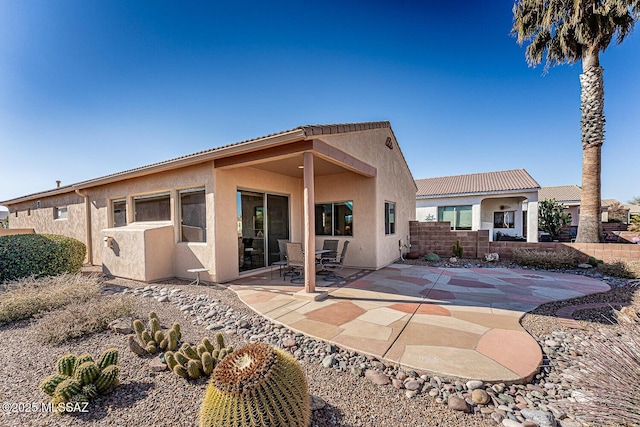 back of property featuring a tile roof, a patio, and stucco siding