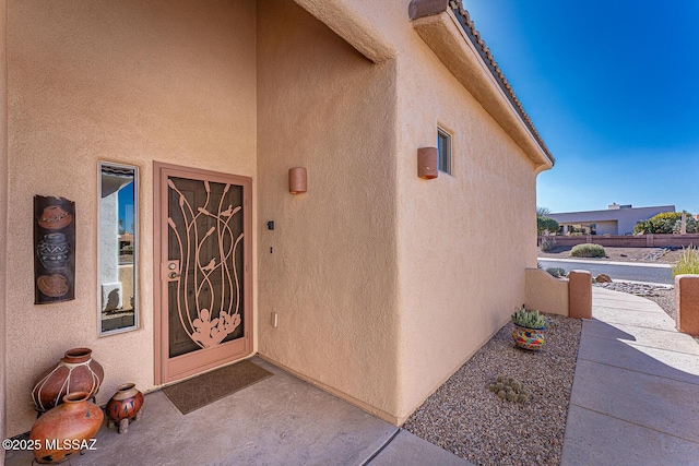 view of exterior entry with a patio and stucco siding