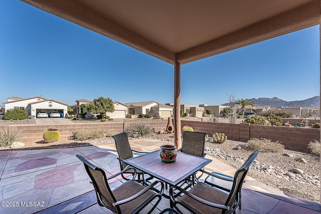 view of patio / terrace with a residential view, outdoor dining area, a fenced backyard, and a mountain view