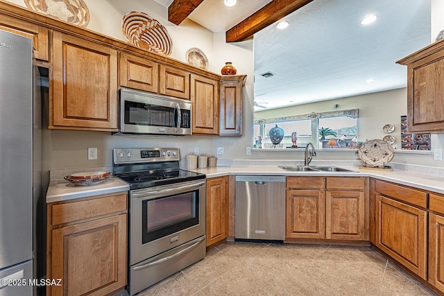 kitchen with appliances with stainless steel finishes, brown cabinets, light countertops, and a sink