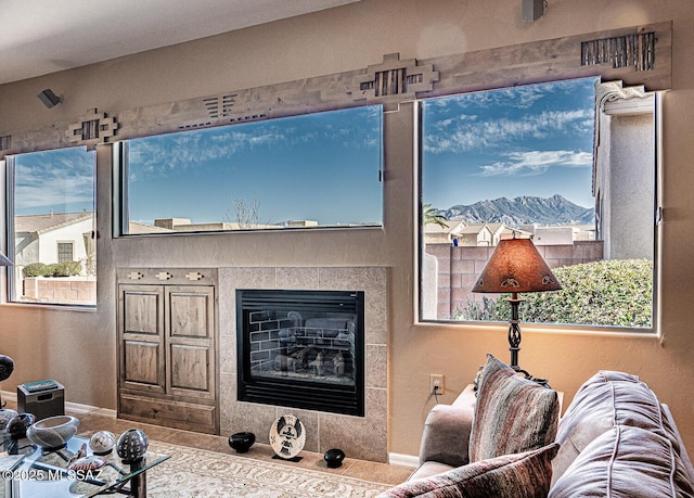 living room featuring a tiled fireplace and baseboards