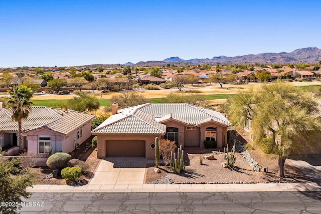 mediterranean / spanish-style home with a mountain view, a garage, a tile roof, concrete driveway, and stucco siding