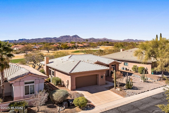 view of front facade with an attached garage, a mountain view, a tile roof, concrete driveway, and stucco siding