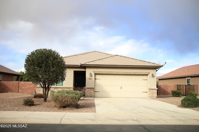 view of front of home with a garage, stone siding, driveway, and fence