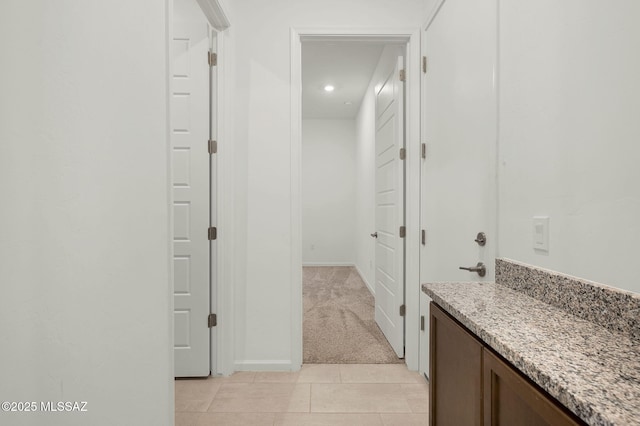 interior space featuring light carpet, light tile patterned floors, and baseboards
