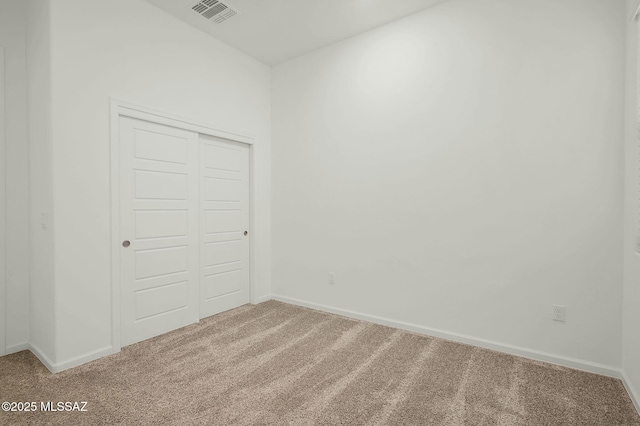 unfurnished bedroom with light colored carpet, a closet, visible vents, and baseboards