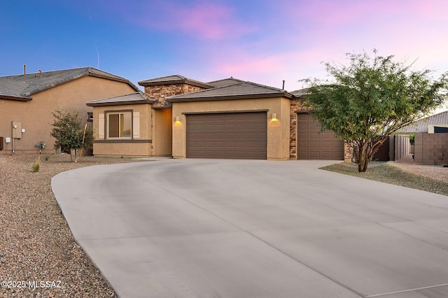 view of front of property with driveway, stone siding, an attached garage, and stucco siding