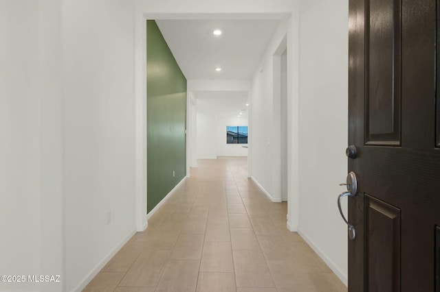 hallway featuring recessed lighting, baseboards, and light tile patterned floors