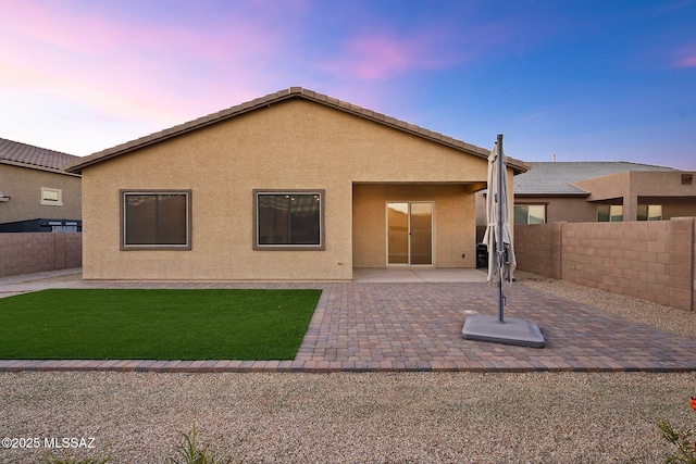 back of property featuring a yard, fence private yard, a patio area, and stucco siding