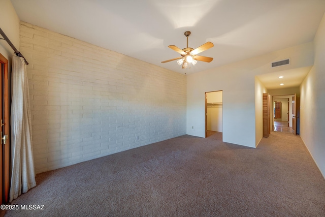 interior space featuring brick wall, carpet, visible vents, and a ceiling fan