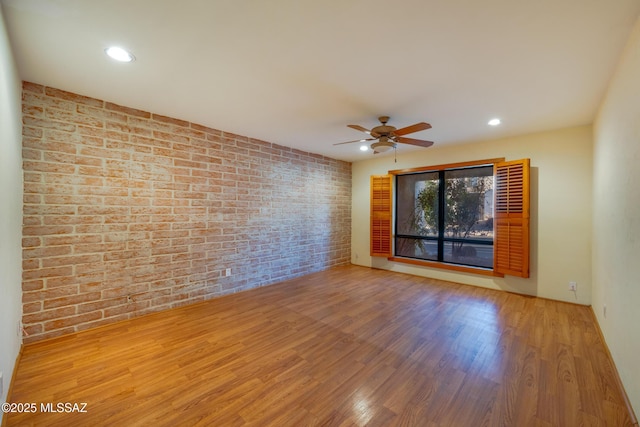 unfurnished room featuring brick wall, wood finished floors, a ceiling fan, and recessed lighting