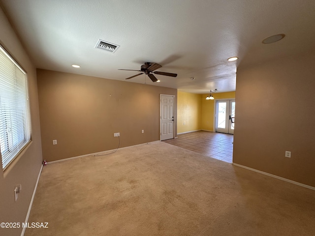 carpeted spare room featuring ceiling fan, a textured ceiling, visible vents, french doors, and tile patterned floors