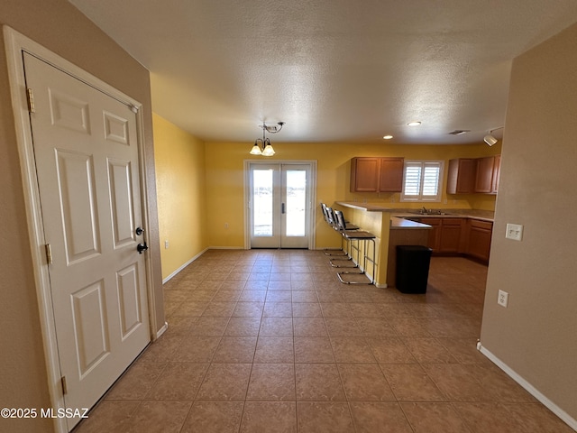 kitchen with french doors, baseboards, a sink, and a kitchen breakfast bar