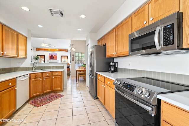 kitchen with appliances with stainless steel finishes, sink, light tile patterned floors, ceiling fan, and kitchen peninsula