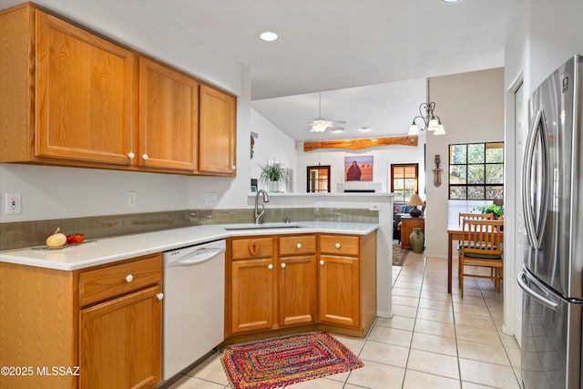 kitchen with kitchen peninsula, stainless steel refrigerator, sink, white dishwasher, and light tile patterned floors