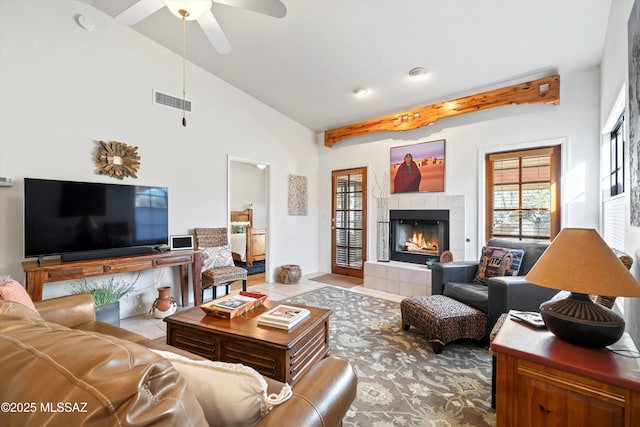 tiled living room featuring ceiling fan, a tile fireplace, and high vaulted ceiling