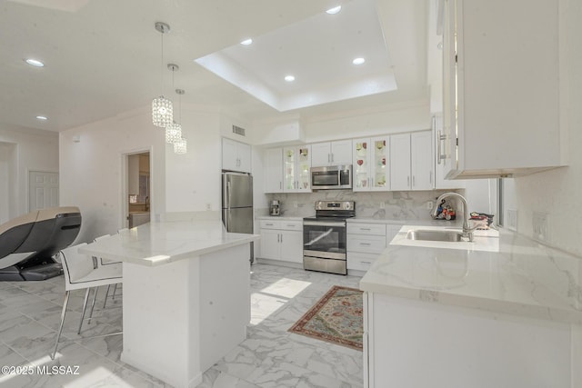 kitchen featuring decorative light fixtures, a sink, white cabinetry, appliances with stainless steel finishes, and glass insert cabinets