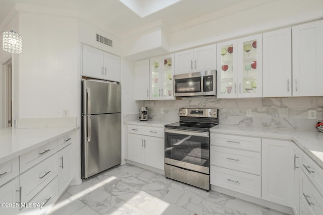 kitchen featuring white cabinetry, glass insert cabinets, stainless steel appliances, and decorative backsplash