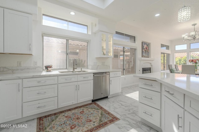 kitchen with marble finish floor, stainless steel dishwasher, white cabinetry, pendant lighting, and a sink