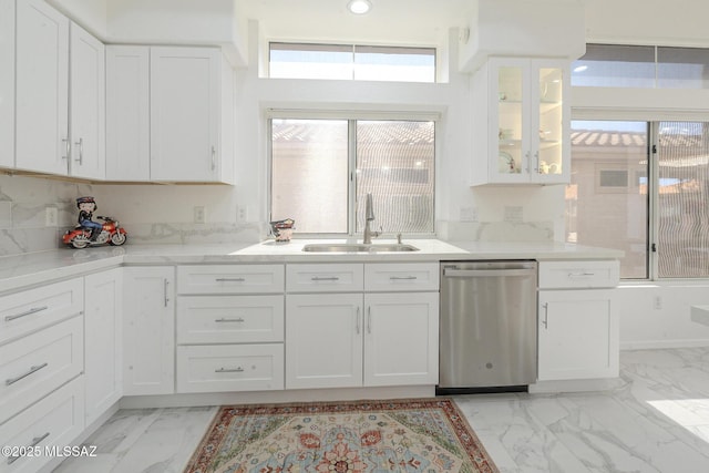 kitchen featuring glass insert cabinets, marble finish floor, stainless steel dishwasher, white cabinetry, and a sink