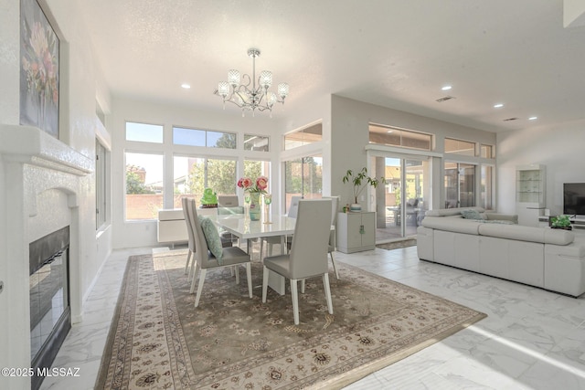 dining space with a glass covered fireplace, marble finish floor, and a healthy amount of sunlight