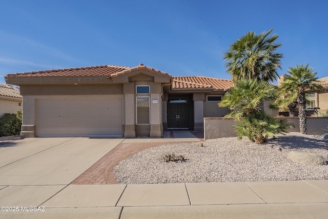 view of front of house featuring a garage, a tile roof, driveway, and stucco siding