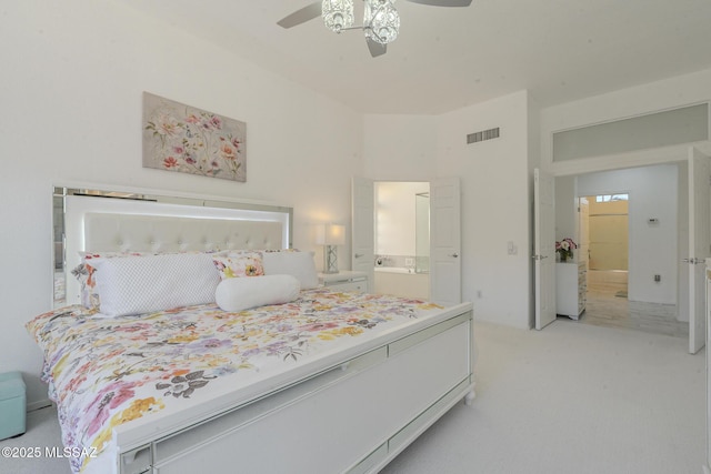 bedroom with light carpet, visible vents, a ceiling fan, and ensuite bathroom