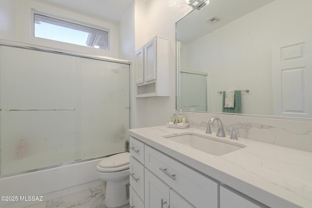 bathroom featuring toilet, visible vents, vanity, marble finish floor, and combined bath / shower with glass door