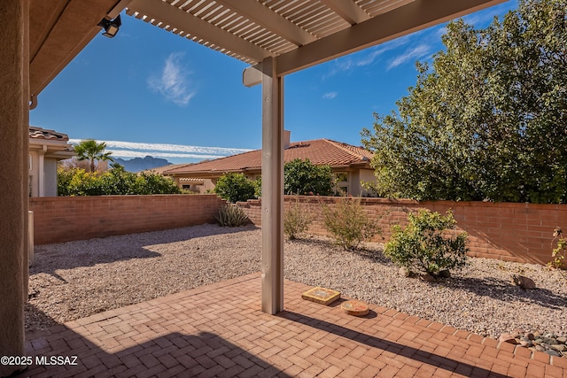 view of patio featuring a fenced backyard, a mountain view, and a pergola