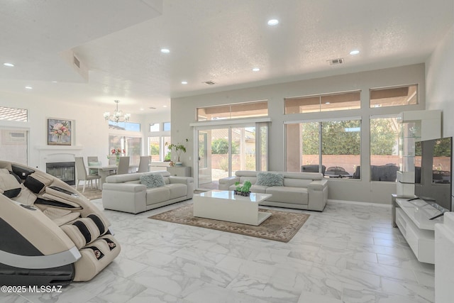 living room with a textured ceiling, marble finish floor, a notable chandelier, and recessed lighting