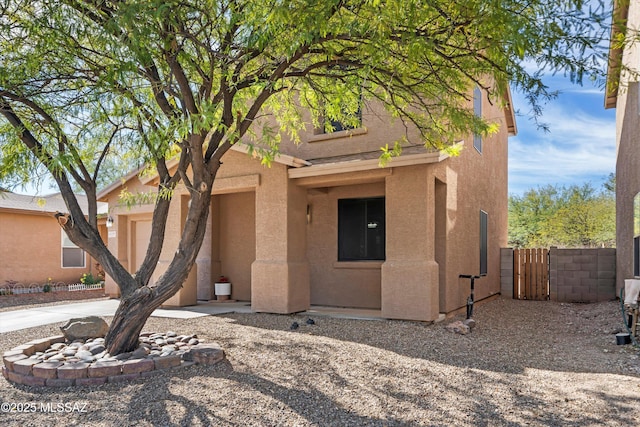 view of front of home featuring fence, an attached garage, and stucco siding