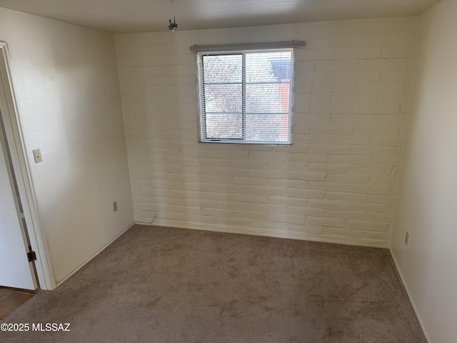 carpeted spare room with brick wall