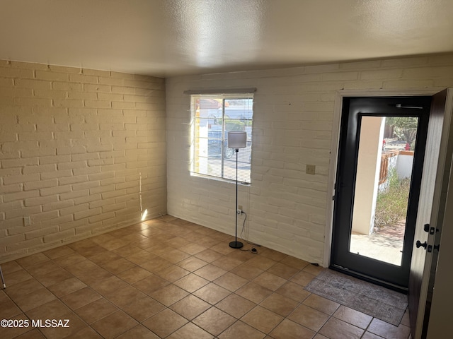 foyer featuring brick wall and a textured ceiling