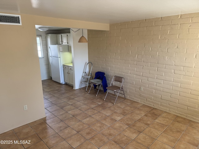 unfurnished dining area with brick wall and light tile patterned floors