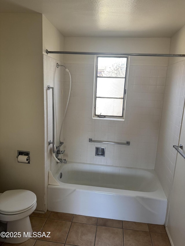 bathroom featuring a textured ceiling, tile patterned flooring, toilet, and tiled shower / bath