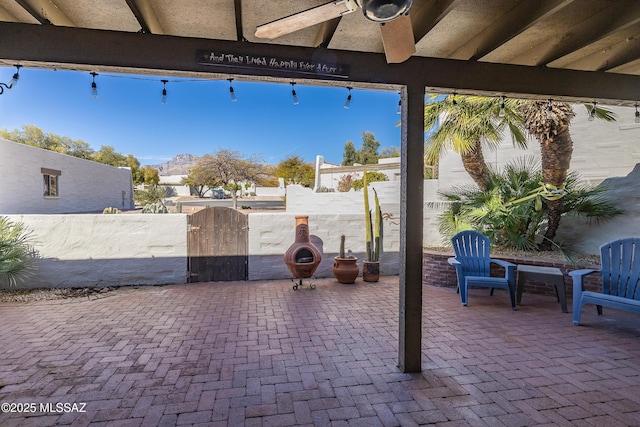 view of patio featuring fence, a gate, and a ceiling fan