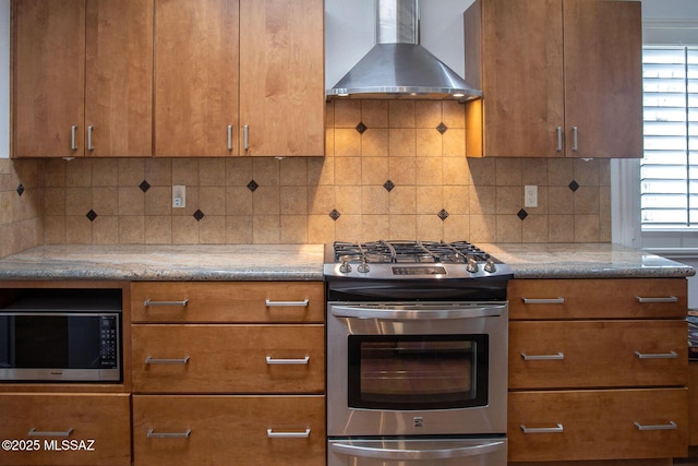 7471 E Serenity Ln, Tucson, AZ 85750 - kitchen with stainless steel appliances, wall chimney exhaust hood, brown cabinets, light stone counters, and decorative backsplash
