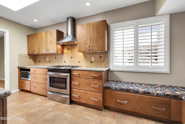 kitchen featuring light tile patterned floors, wall chimney exhaust hood, appliances with stainless steel finishes, and backsplash