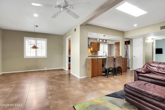 living room featuring light tile patterned floors, ceiling fan, visible vents, and baseboards