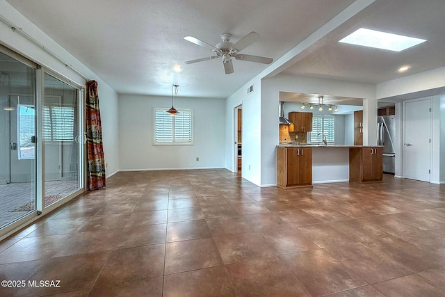 7471 E Serenity Ln, Tucson, AZ 85750 - unfurnished living room with baseboards, dark tile patterned floors, a sink, a skylight, and ceiling fan