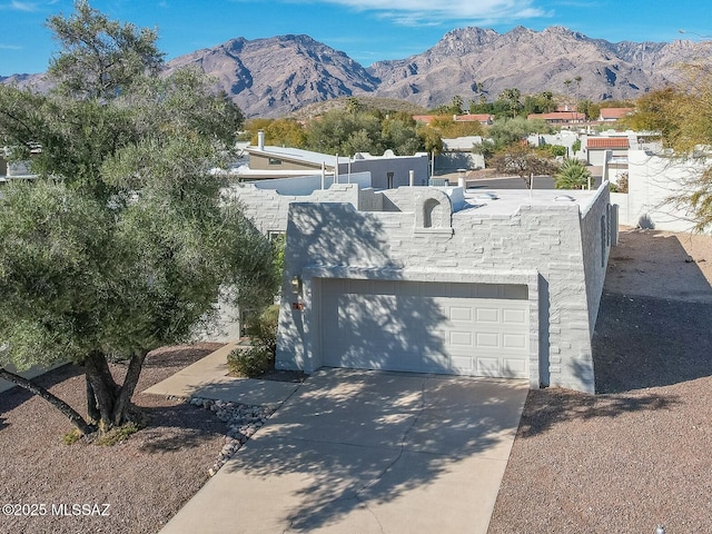 view of front of property featuring a garage, driveway, a mountain view, and stucco siding