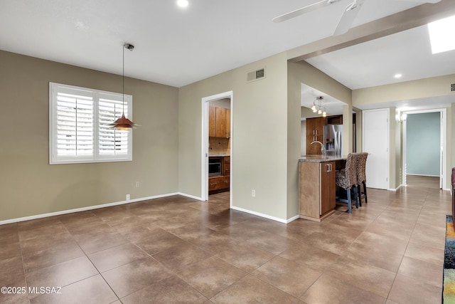 interior space featuring tile patterned flooring, a sink, a ceiling fan, visible vents, and baseboards