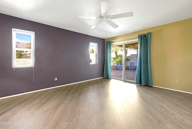 empty room featuring ceiling fan, wood finished floors, and baseboards