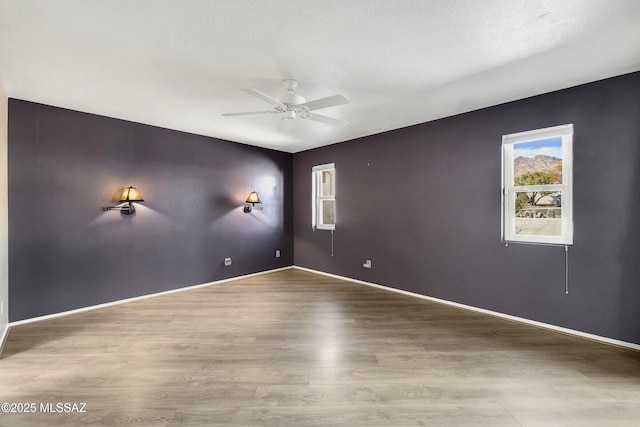 unfurnished room with light wood-style flooring, a textured ceiling, baseboards, and a ceiling fan