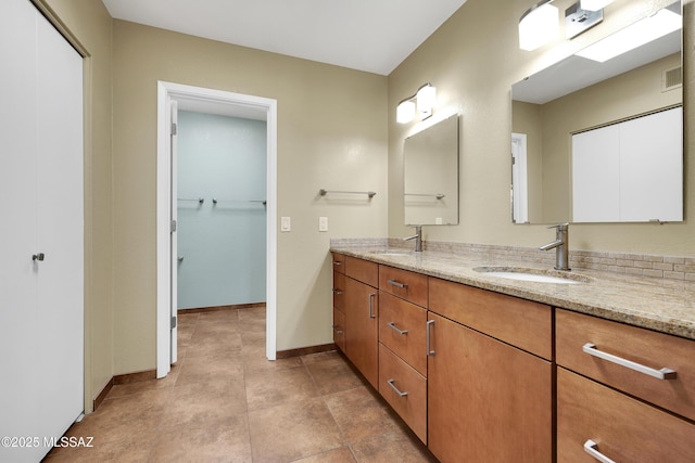 bathroom with visible vents, a sink, baseboards, and double vanity