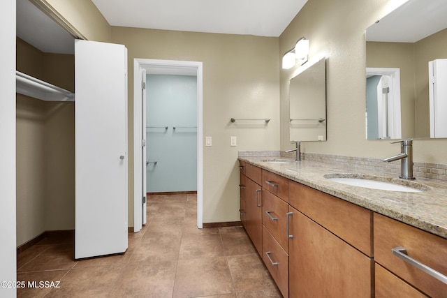 bathroom with double vanity, baseboards, and a sink