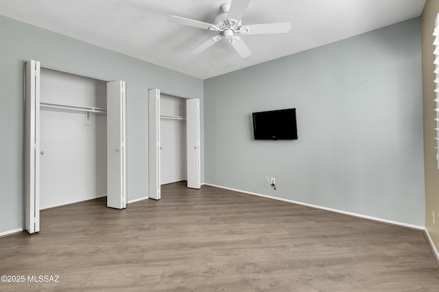 unfurnished bedroom with baseboards, a ceiling fan, light wood-style flooring, and multiple closets