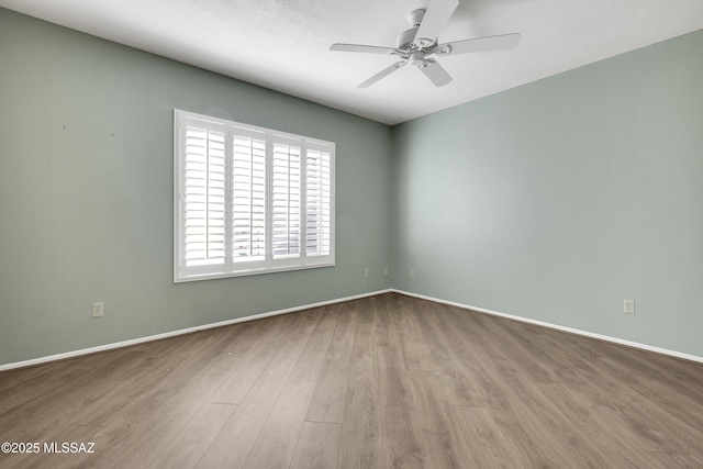 spare room with baseboards, a ceiling fan, and light wood-style floors